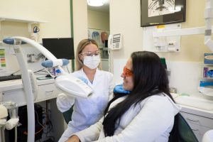 Dental professional conducting chairside teeth whitening treatment on a patient, showcasing the process of professional whitening for enhanced smiles.
