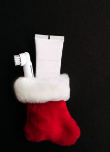 Red Christmas stocking filled with a toothbrush and toothpaste, symbolizing dental-friendly holiday gifts.