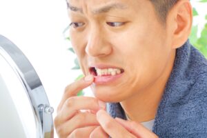 man checking tooth in mirror