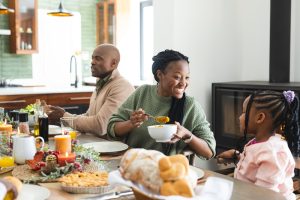 Family enjoying Thanksgiving meal at a festive table with various dishes, highlighting the importance of dental care during holiday feasting.